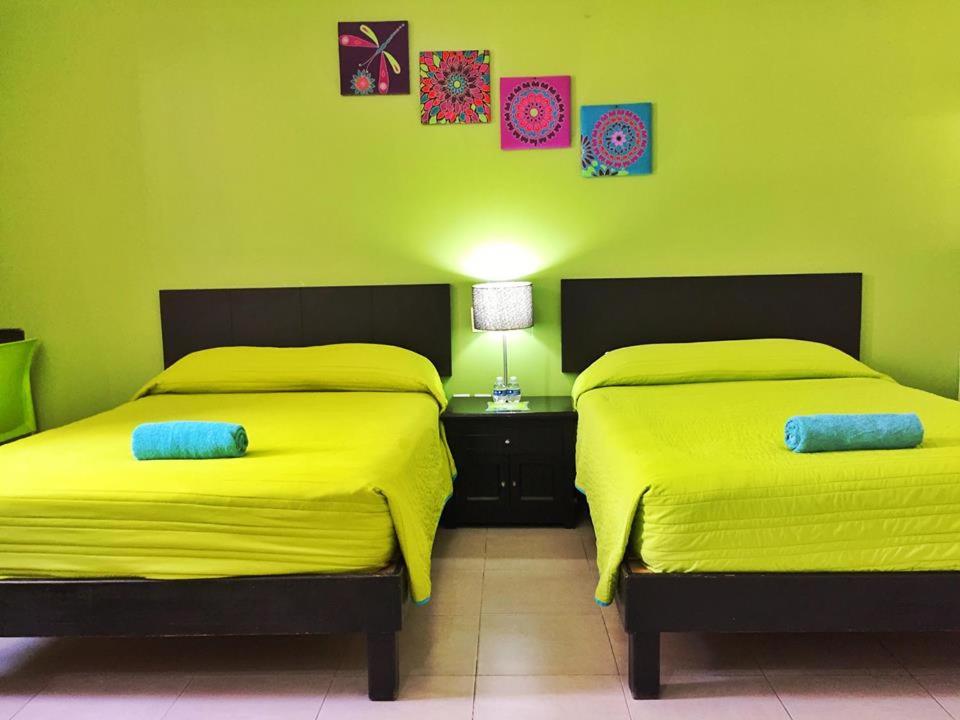 two beds in a room with green walls at Hotel Plazha in Tuxtla Gutiérrez