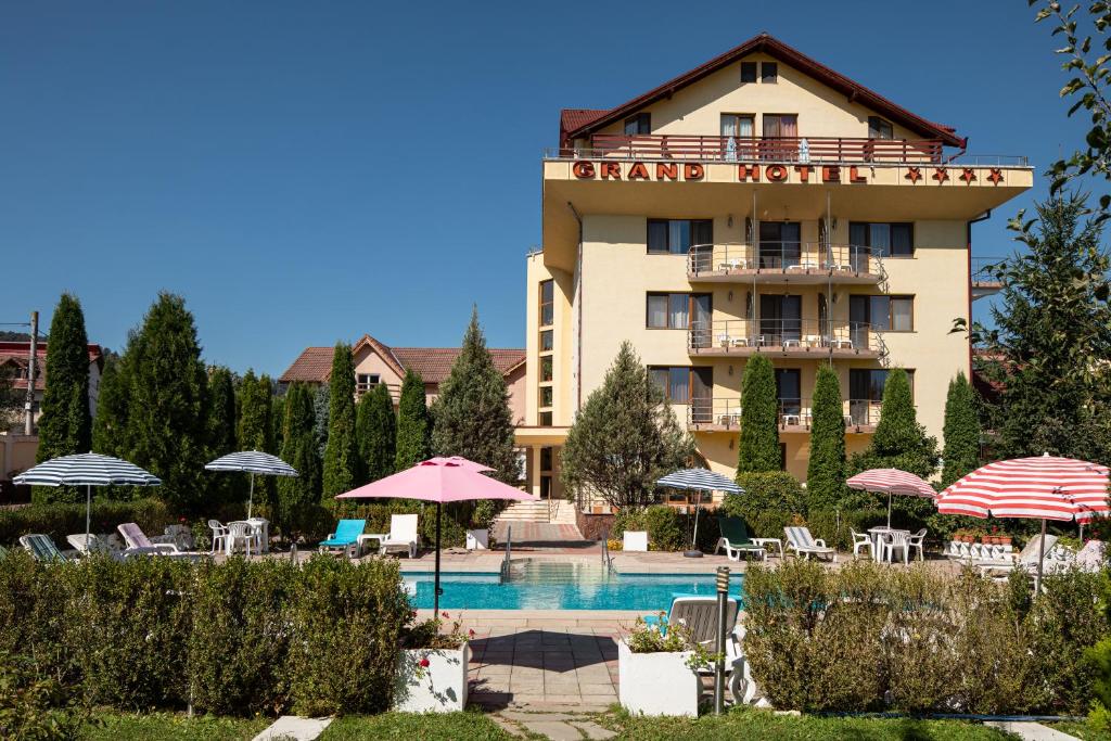 ein Hotel mit einem Pool, Stühlen und Sonnenschirmen in der Unterkunft Grand Hotel in Braşov