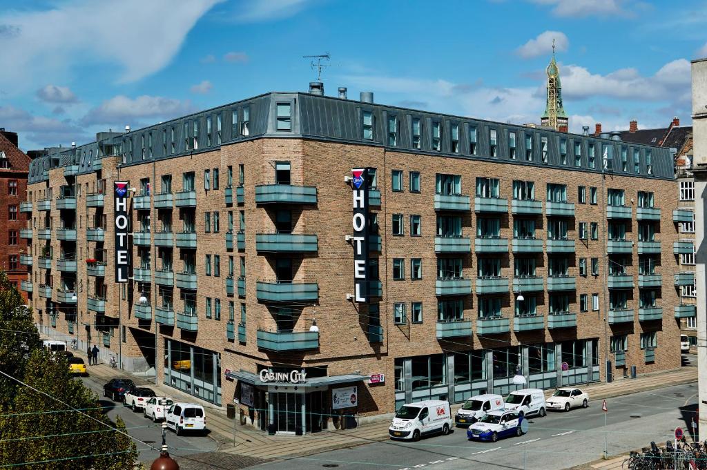 ein großes Backsteingebäude mit Autos auf einem Parkplatz in der Unterkunft Cabinn City in Kopenhagen