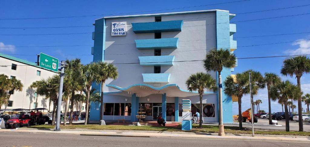 a building with palm trees in front of it at Fountain Beach Resort - Daytona Beach in Daytona Beach