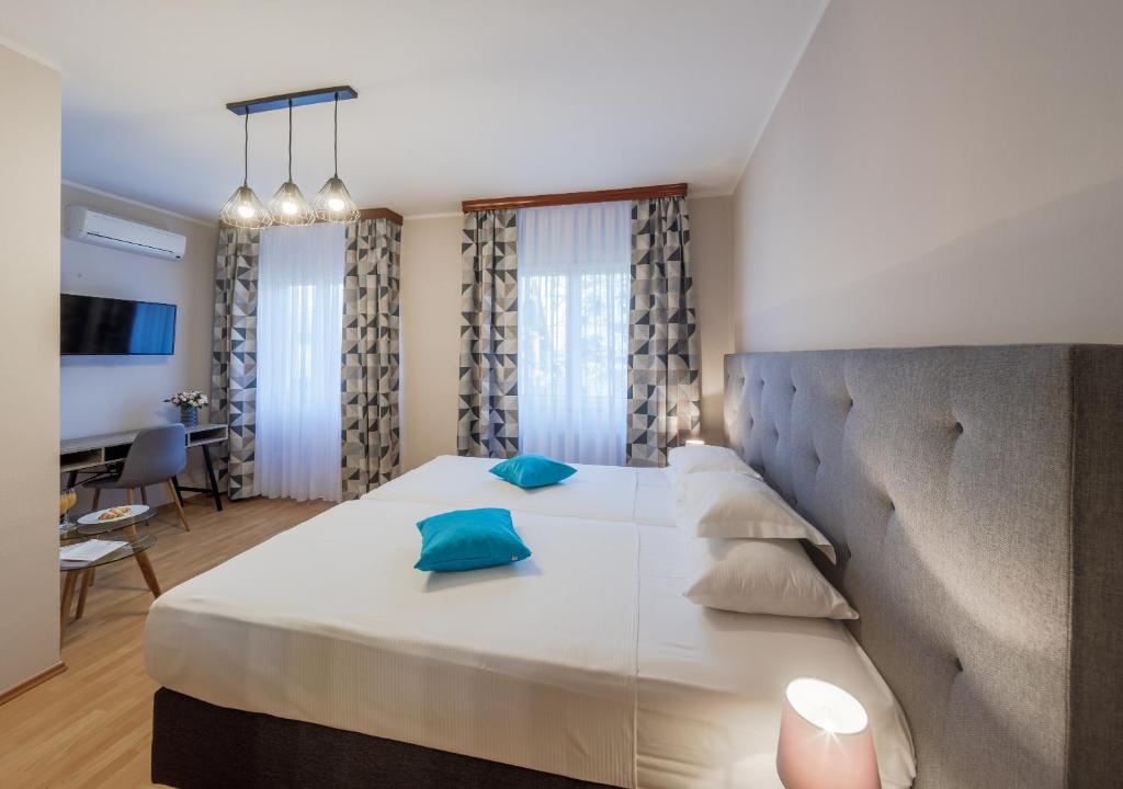 a bedroom with a large white bed with blue pillows at Pansion Waldinger in Osijek