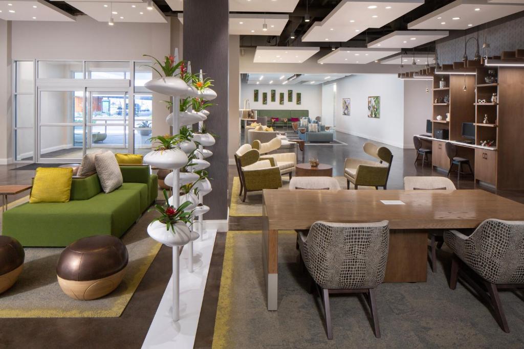 a lobby with a green couch and a table and chairs at Hotel Indigo Gainesville-Celebration Pointe, an IHG Hotel in Gainesville