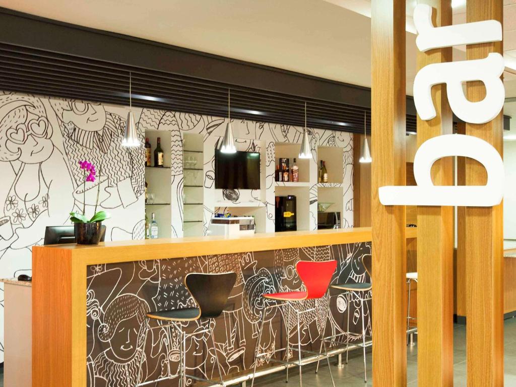 un bar con due sedie rosse in un ristorante di ibis Cascavel a Cascavel