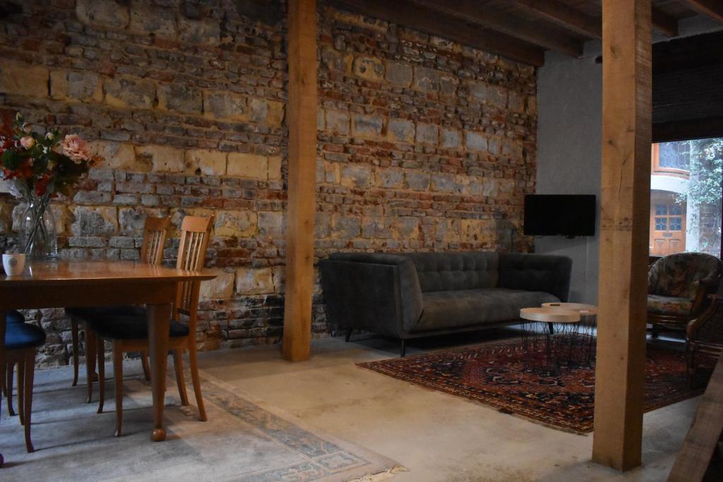 een woonkamer met een tafel en een bakstenen muur bij Roermond Uniek Stadspand, compleet woonhuis in Roermond