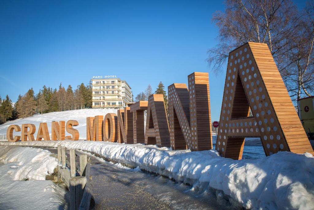 een gebouw met een bord in de sneeuw bij Grand Hôtel du Parc in Crans-Montana