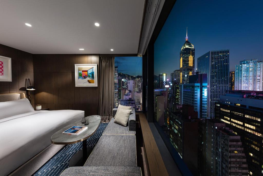 a hotel room with a bed and a view of a city at The Hari Hong Kong in Hong Kong