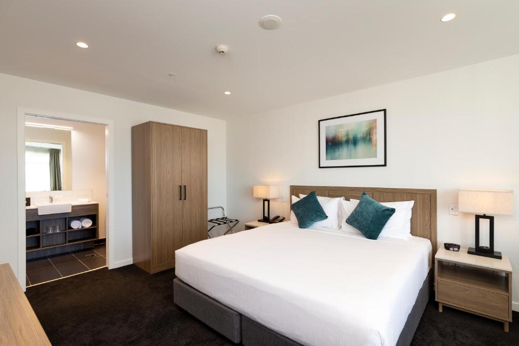 a bedroom with a large white bed and a bathroom at Nesuto Stadium in Auckland