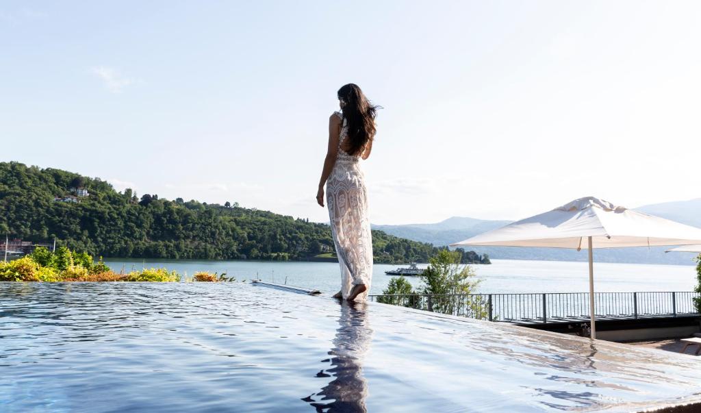 a woman standing on the edge of a swimming pool at Hotel de Charme Laveno in Laveno-Mombello