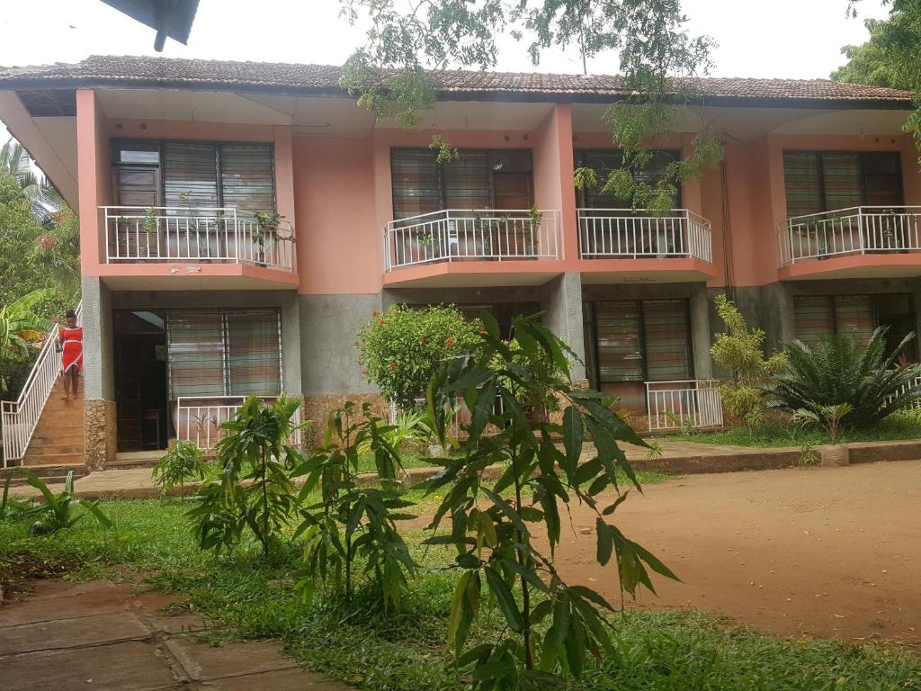 un edificio con balcones y árboles delante de él en PRIMESHADE GUESTHOUSE, en Malindi