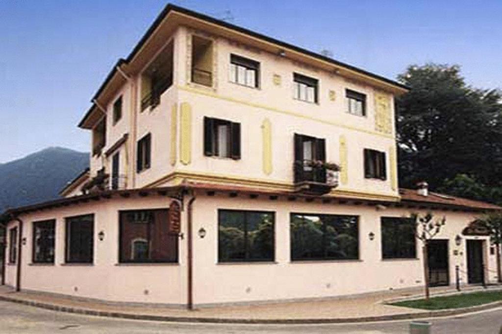 a large white building with windows on a street at Hotel La Bussola in Cittiglio