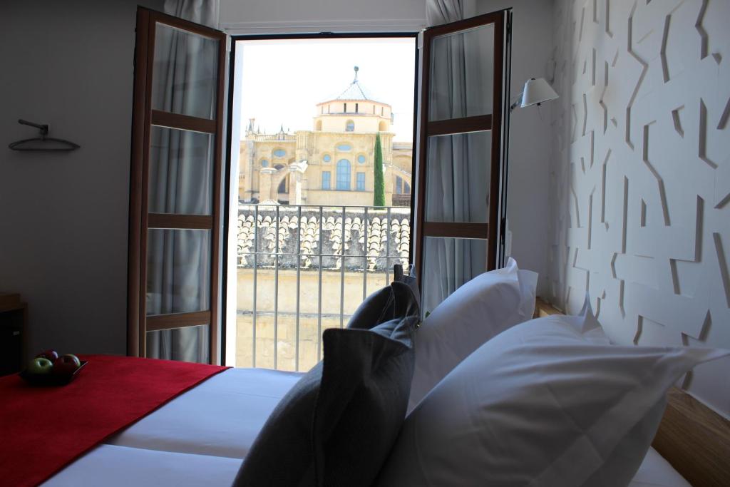 1 dormitorio con vistas a una iglesia a través de una ventana en Hotel Boutique Caireles, en Córdoba