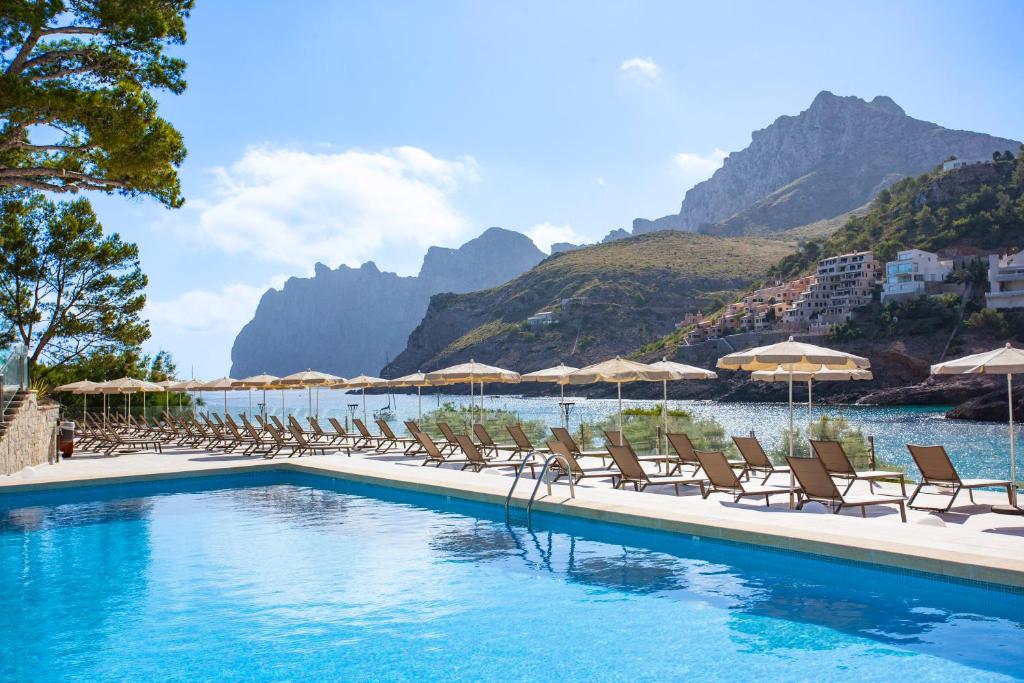 une piscine avec des chaises et des parasols et une montagne dans l'établissement Grupotel Molins, à Cala Sant Vicenç