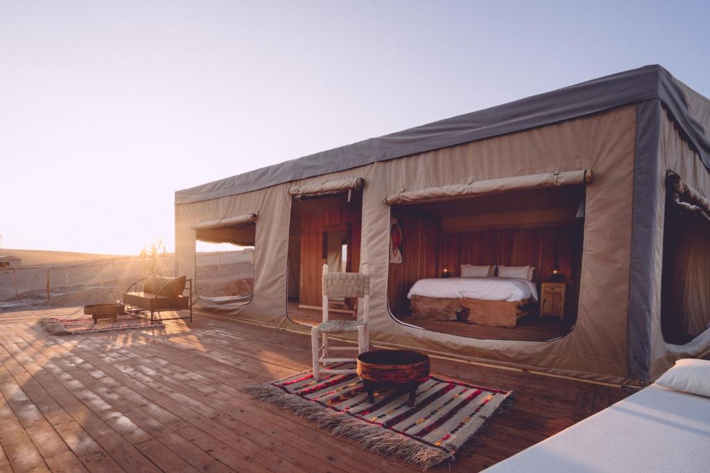 ein Schlafzimmer in einem Zelt mit einem Bett auf einer Terrasse in der Unterkunft Dar Inacamp in El Mjed