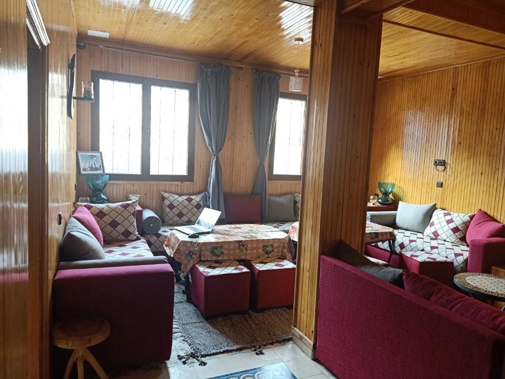 ein Wohnzimmer mit Sofas, einem Tisch und Fenstern in der Unterkunft Atlas Chalet Armed in Imlil