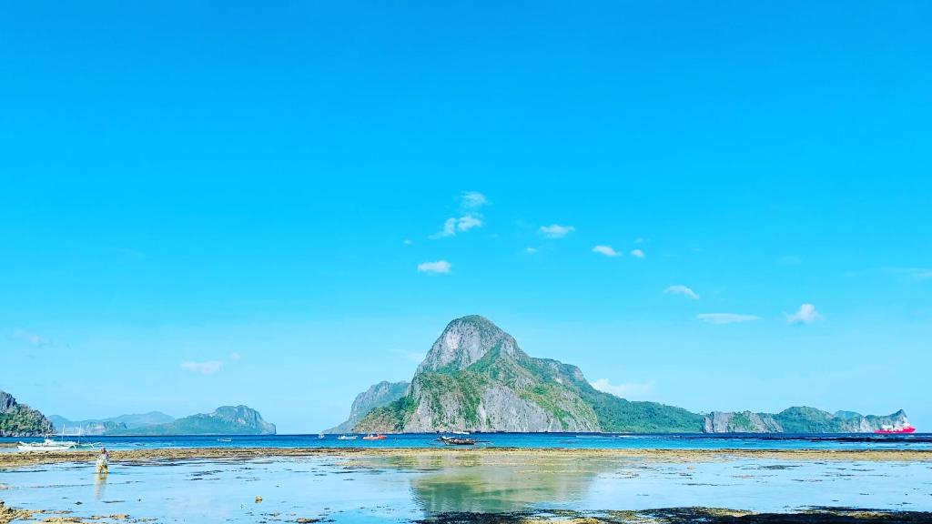 Blick auf einen Strand mit einem Berg im Wasser in der Unterkunft Hidden of Cailan Inn in El Nido