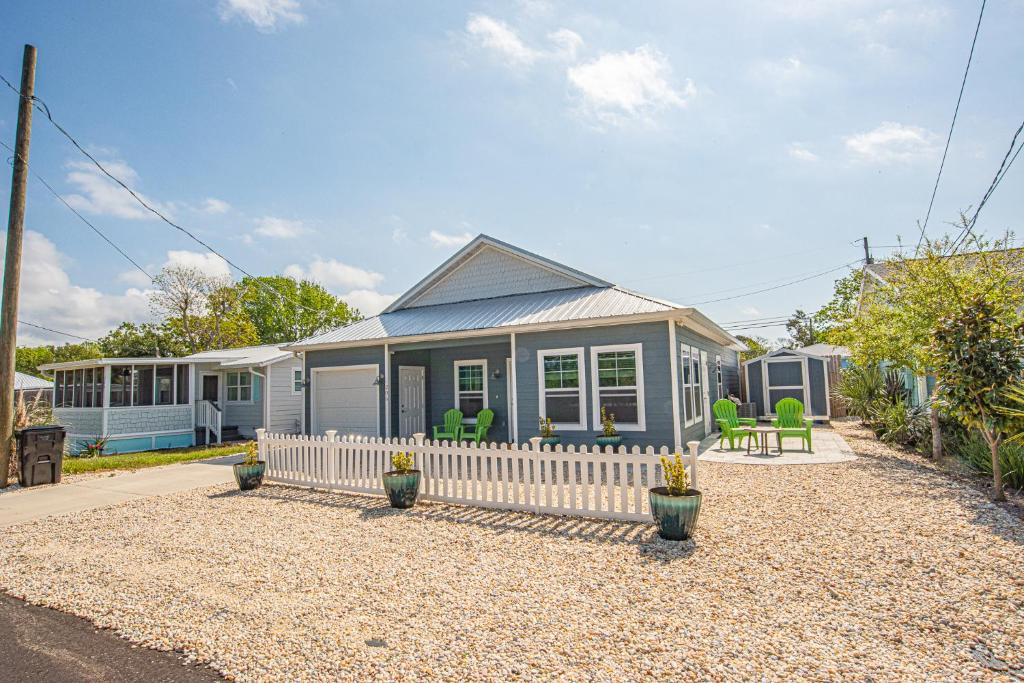 a small blue house with green chairs in a yard at Beach Daze in Panama City Beach