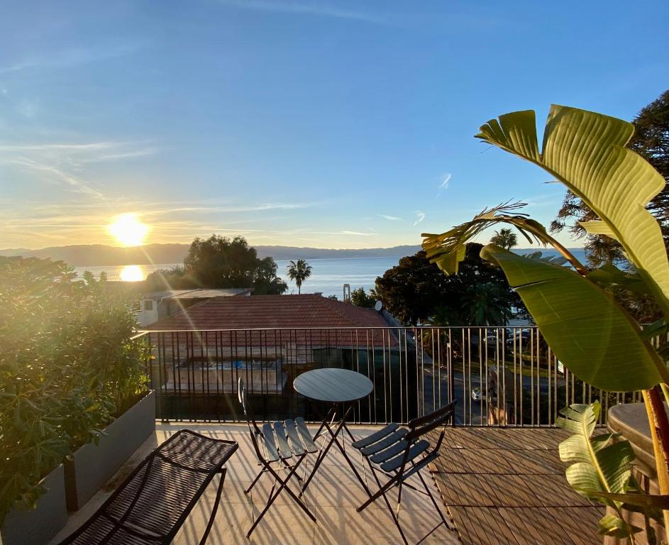 a table and chairs on a deck with the sunset at Malalbergo in Reggio di Calabria