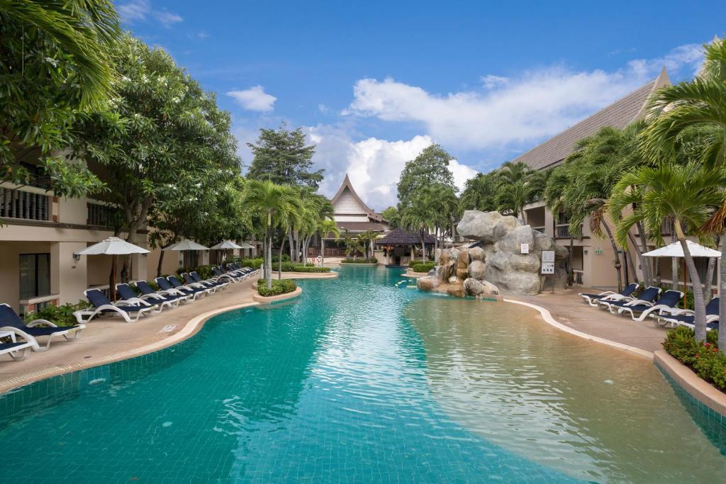 una piscina in un resort con sedie e scivolo d'acqua di Centara Kata Resort Phuket a Kata Beach