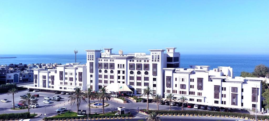 a large white building in front of the ocean at Safir Fintas Hotel Kuwait in Kuwait