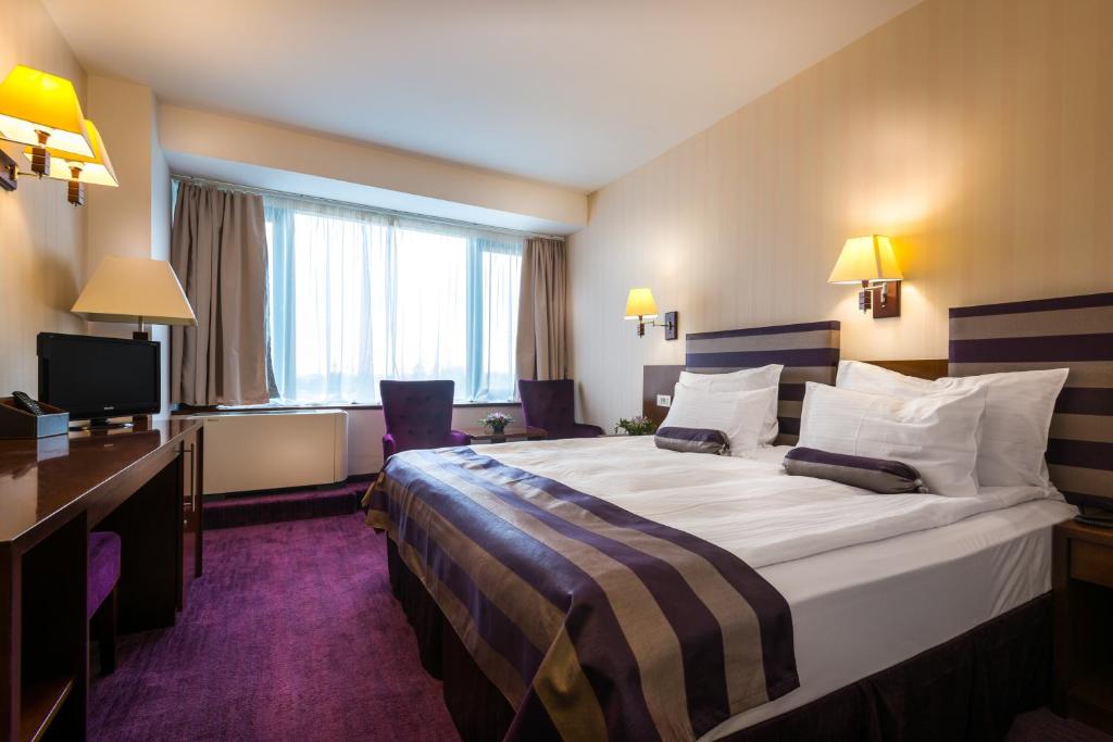 a hotel room with a large bed and a television at Grand Hotel Napoca in Cluj-Napoca