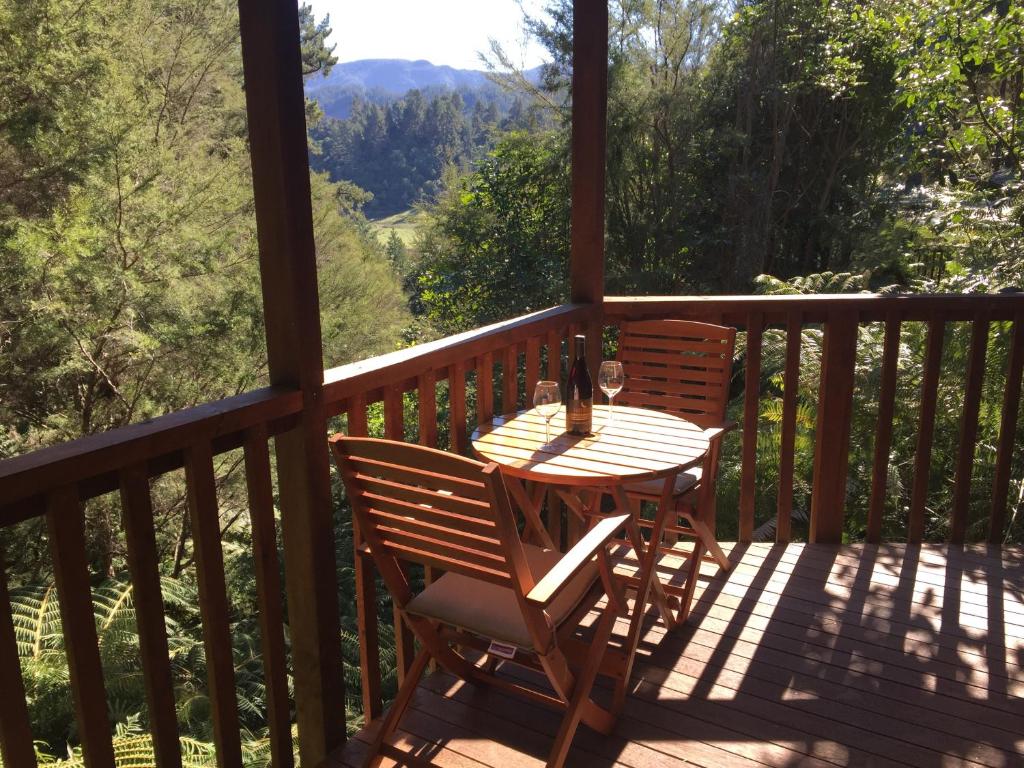 a wooden deck with a table and chairs on it at Kanuka Ridge Lodge in Marahau