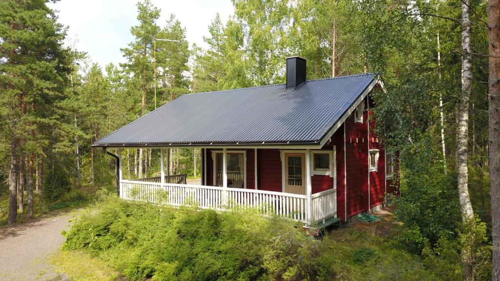 a red house with a black roof in the woods at Lomahyppäys in Naantali