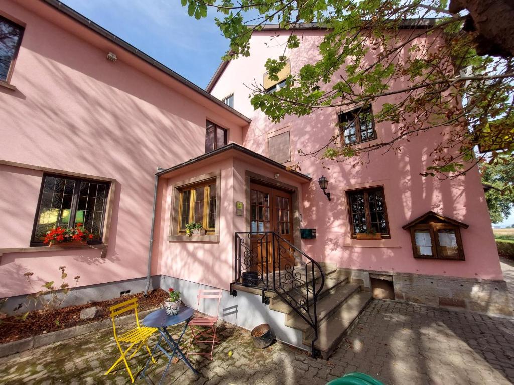 une maison rose avec une table et des chaises devant elle dans l'établissement Auberge De La Foret - Logis, à Vendenheim