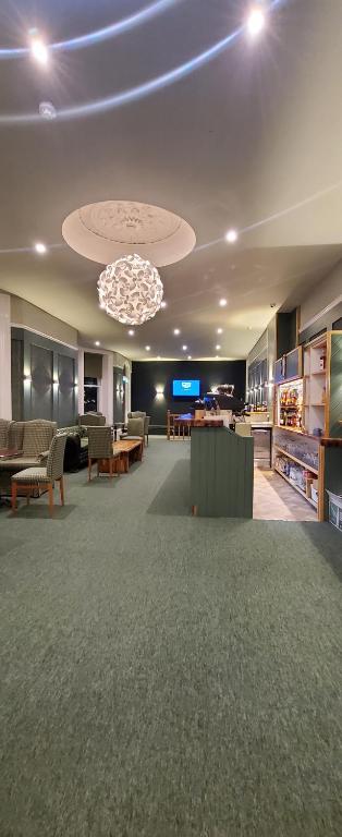 a lobby with a large room with chairs and a chandelier at Alexandra Hotel in Eastbourne