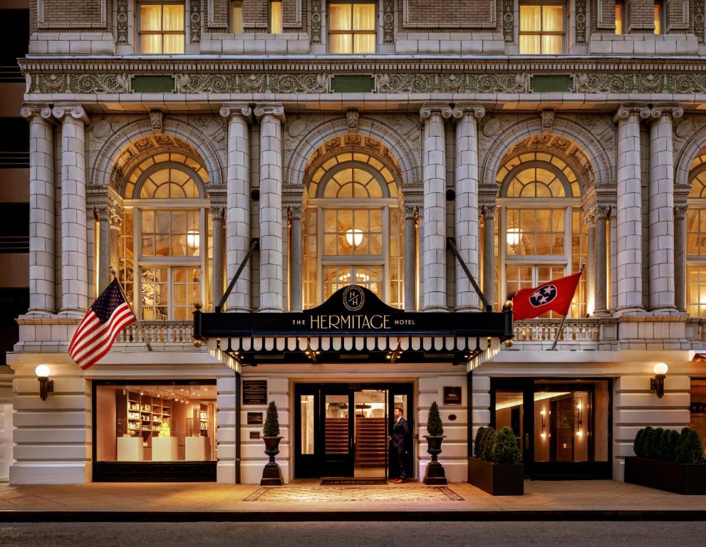 een gebouw waar een vrouw buiten staat bij The Hermitage Hotel in Nashville