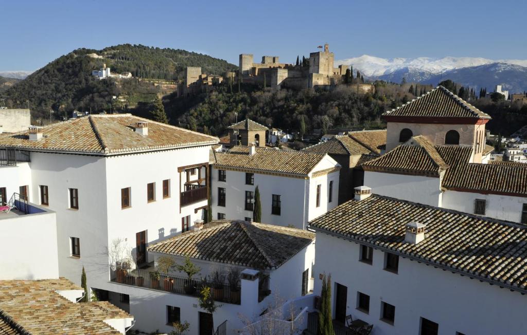 vista sui tetti delle case con un castello sullo sfondo di Smart Suites Albaicin a Granada