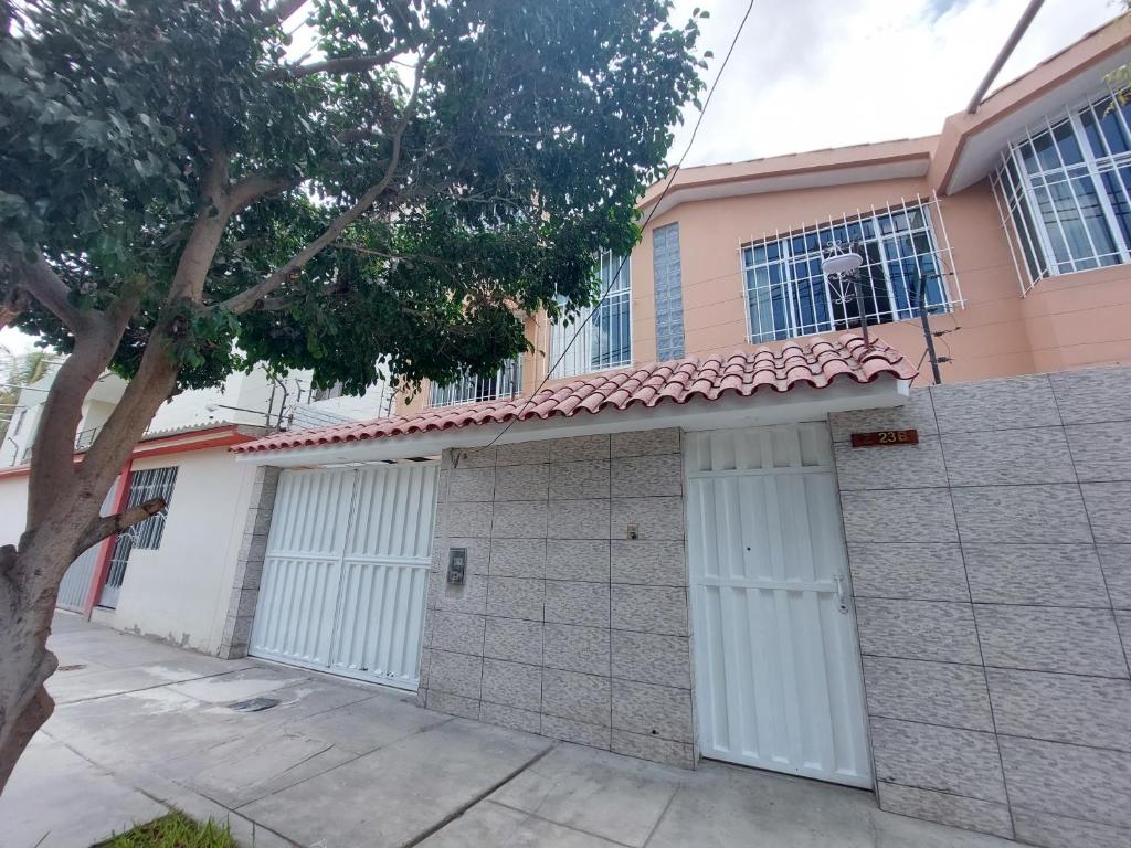 una casa con dos puertas de garaje y un árbol en CASA ARENA, en Piura