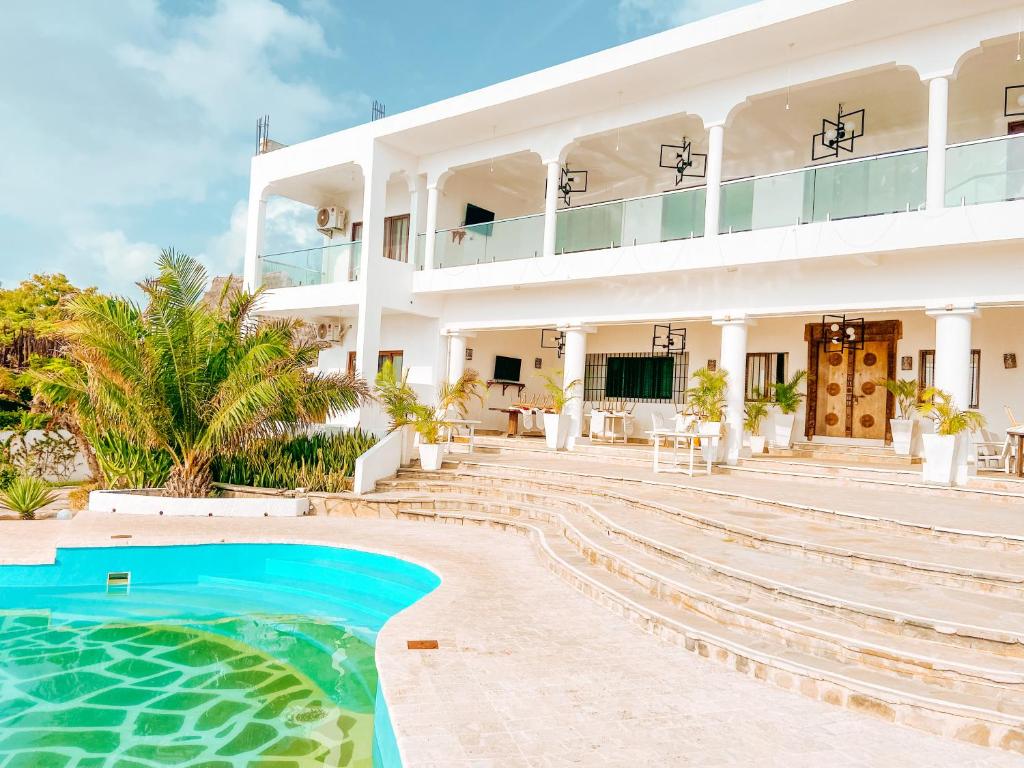 - un grand bâtiment blanc avec une piscine en face dans l'établissement Met Beach Resort Malindi, à Malindi