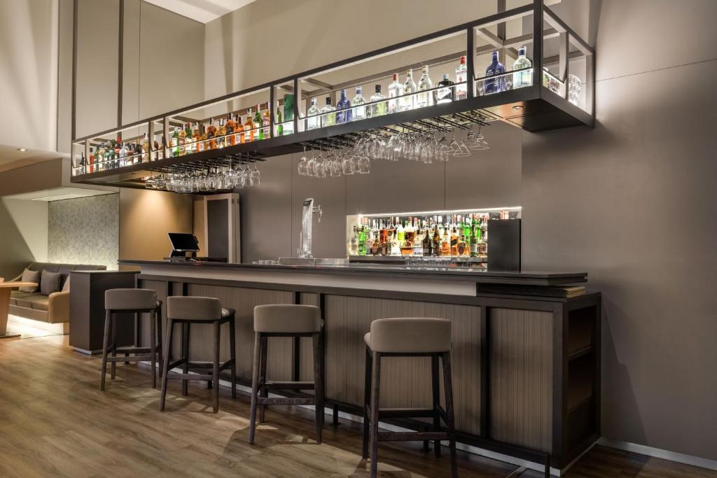 un bar con taburetes y un estante con bebidas en AC Hotel Córdoba by Marriott, en Córdoba