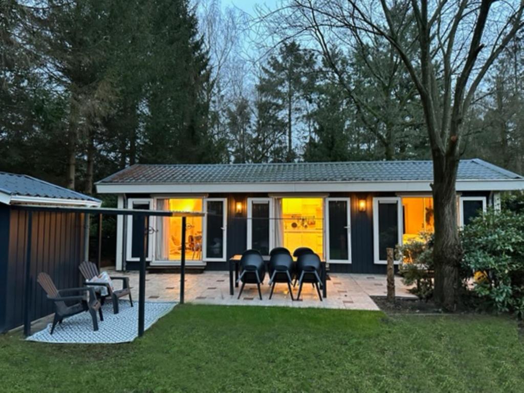 a patio with black chairs and a house at Stayatsas Tiny House Julia in de bossen op de Veluwe! in Epe