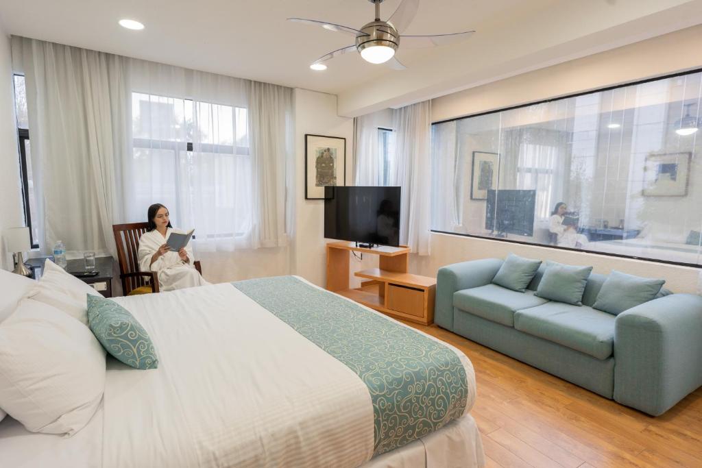 a woman in a hotel room with a bed and a couch at Suites Coben Apartamentos Amueblados in Mexico City