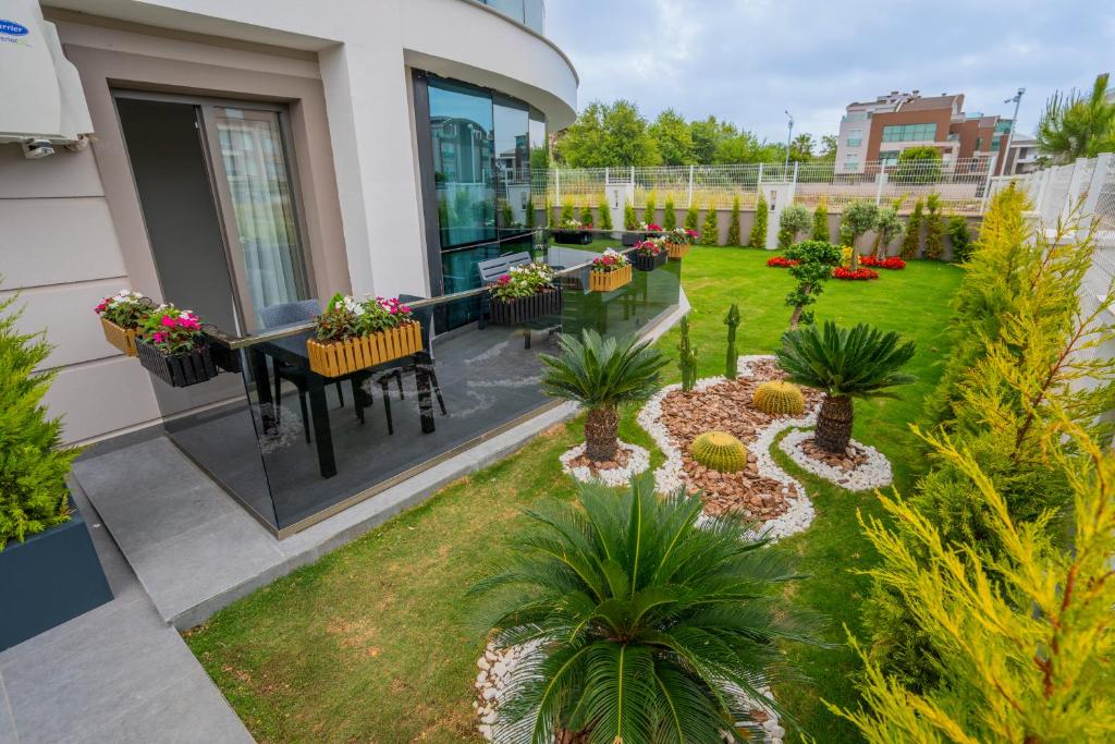 um pátio exterior com uma mesa, cadeiras e plantas em LARA MARİNE HOMES em Antália