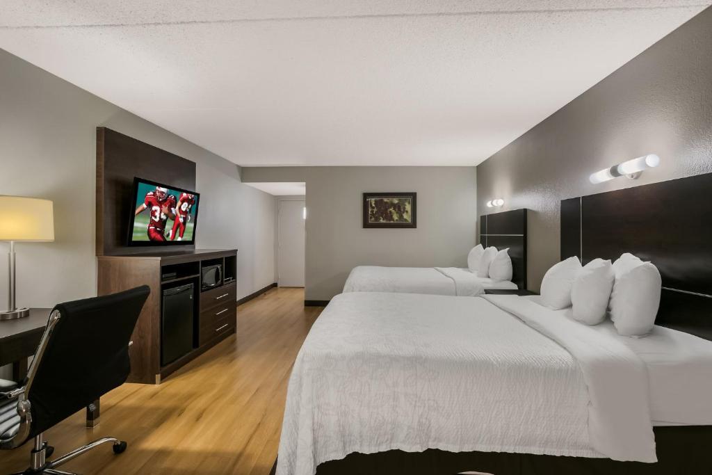 een hotelkamer met 2 bedden, een bureau en een televisie bij Red Roof Inn PLUS+ & Suites Knoxville West - Cedar Bluff in Knoxville