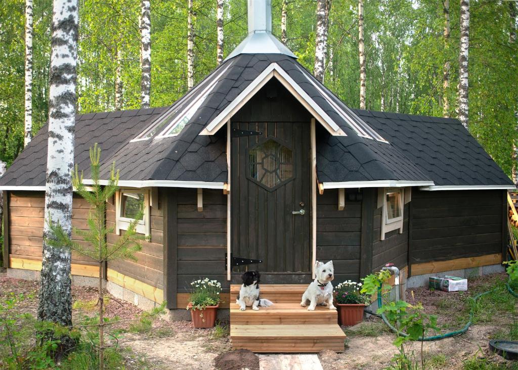 dwa psy siedzące na ganku domku dla psów w obiekcie Troll House Eco-Cottage, Nuuksio for Nature lovers, Petfriendly w mieście Espoo