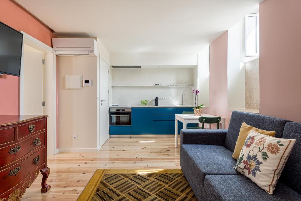 a living room with a blue couch and a kitchen at JOIVY Flats next to Rossio Square and main Lisbon attractions in Lisbon