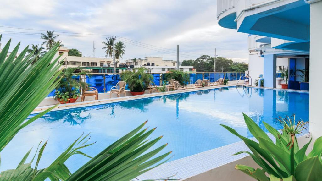 a large blue swimming pool with chairs and plants at Hotel Sapphire in Mombasa