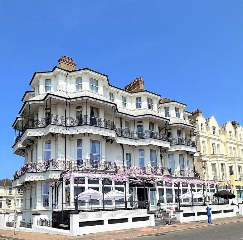 a large white building with balconies on a street at East Beach Hotel in Eastbourne