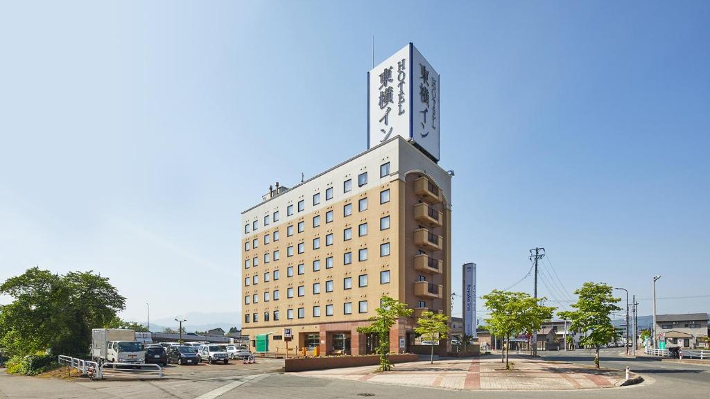 米泽市Toyoko Inn Yonezawa Ekimae的一座高大的建筑,上面有钟