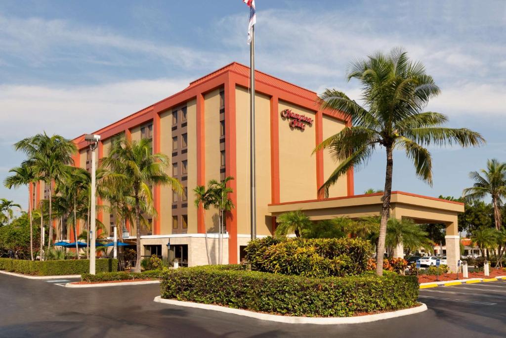 ein orangefarbenes Gebäude mit Palmen vor einer Straße in der Unterkunft Hampton Inn Miami-Airport West in Miami