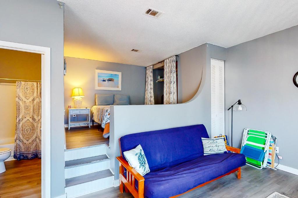 a living room with a blue couch and a bedroom at Okaloosa Island Studio in Fort Walton Beach