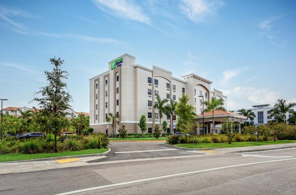 Holiday Inn Express & Suites - Miramar, an IHG Hotel في ميرامار: مبنى ابيض كبير على شارع له طريق