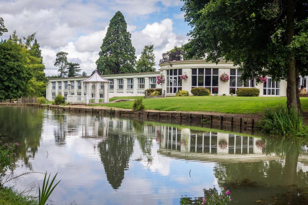 チェルトナムにあるDoubleTree by Hilton Cheltenham-Cotswoldsの湖前の建物