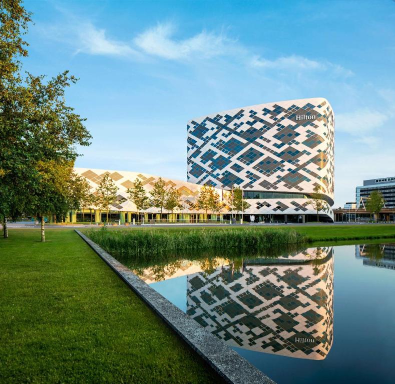 een gebouw met zijn reflectie in een waterlichaam bij Hilton Amsterdam Airport Schiphol in Schiphol