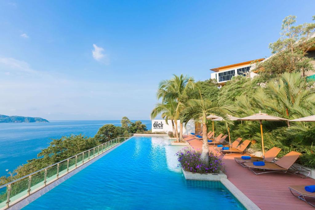 a swimming pool with chairs and the ocean in the background at Wyndham Grand Phuket Kalim Bay in Patong Beach