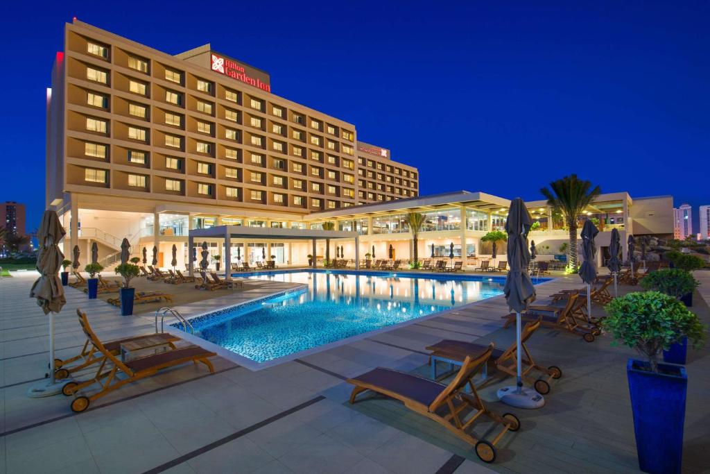 un hôtel avec une piscine ouverte la nuit dans l'établissement Hilton Garden Inn Ras Al Khaimah, à Ras al Khaimah