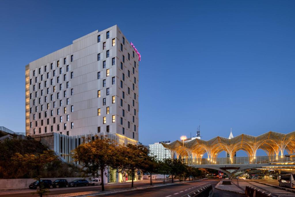 a tall white building on a city street at night at Moxy Lisboa Oriente in Lisbon